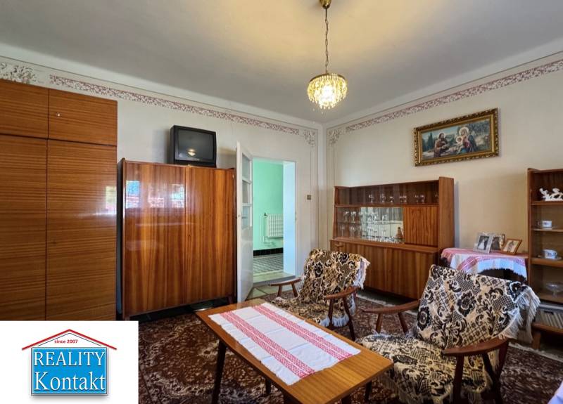 Wohnzimmer in einem Einfamilienhaus mit Teppich, älteren Möbeln und Kronleuchter.