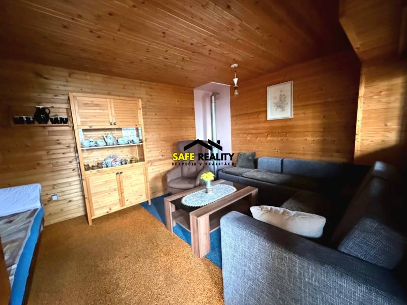 Das Innere der Hütte mit Holzelementen, bequemen Sofas und einer Vitrine für Geschirr.