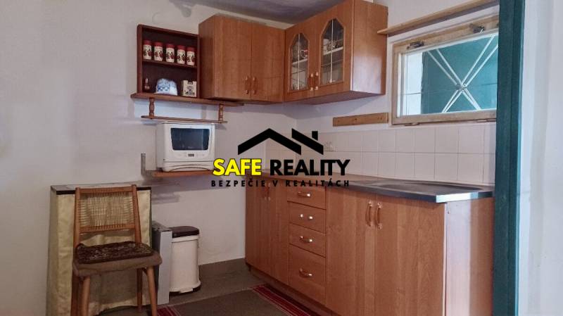 Eine Küche in einer Hütte mit Holzmöbeln und einer Mikrowelle, Boden mit Holzdekor.