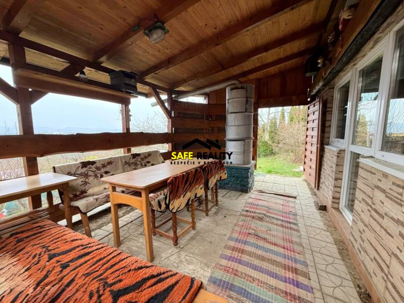 Eine Hütte in Žilina mit Holzmöbeln, Kamin und Blick auf die Natur.