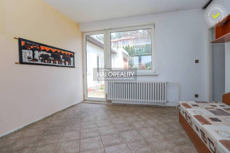 Innenraum eines Einfamilienhauses mit Fliesenboden, Sofa und großem Fenster.