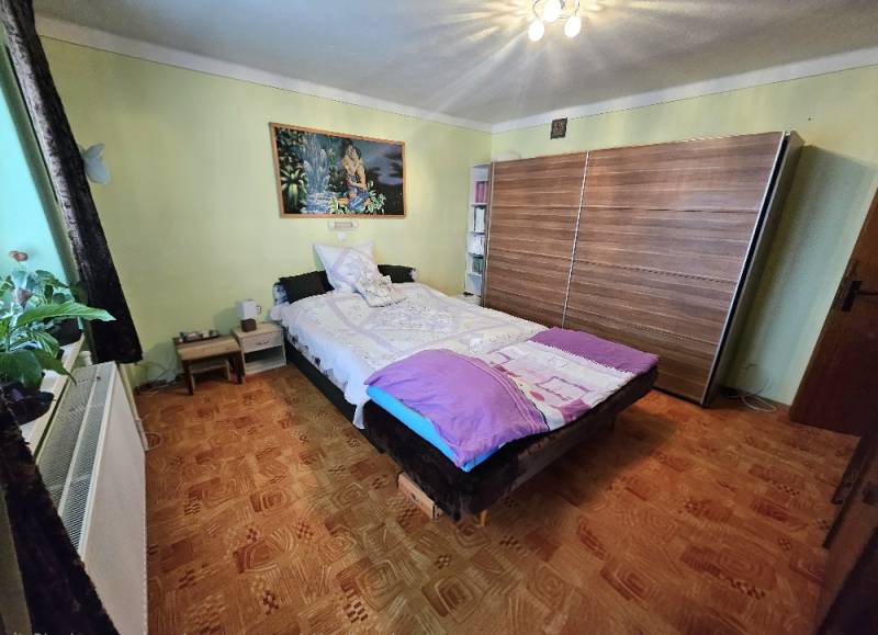 Schlafzimmer in einem Einfamilienhaus mit Bett, Schrank und Bodenbelag in Holzoptik.