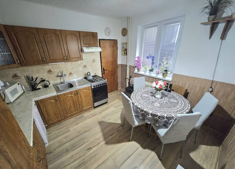 Küche in einem Einfamilienhaus mit Holzdekor, mit Esstisch und Küchenzeile.