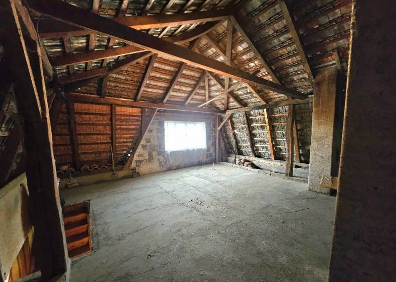 Dachboden eines Einfamilienhauses mit freiliegender Dachkonstruktion und Treppe.