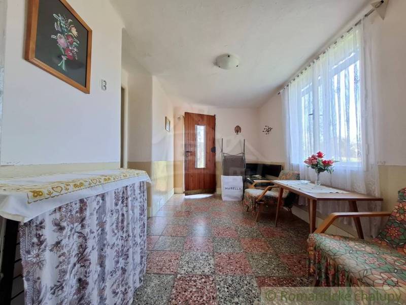 Innenraum eines Einfamilienhauses mit Mosaikboden, dekoriertem Tisch und Blumenschmuck.