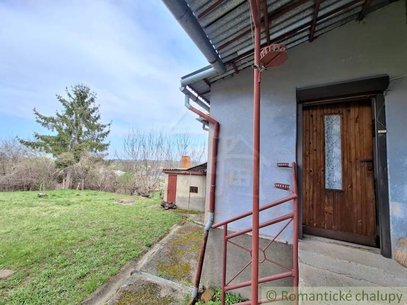Ein Einfamilienhaus in Ľuba mit einem Rasenhof und Holztüren.