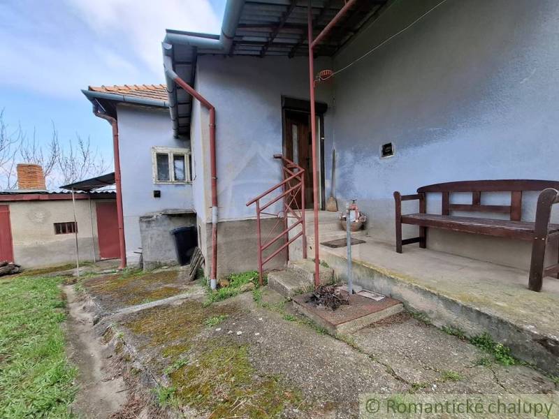 Ein Einfamilienhaus in Ľubá mit einer Bank auf der Betonterrasse und einem grasbewachsenen Hof.