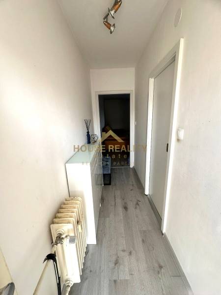 Ein schmaler Flur mit Holzboden und einem Heizkörper in einer 2-Zimmer-Wohnung.
