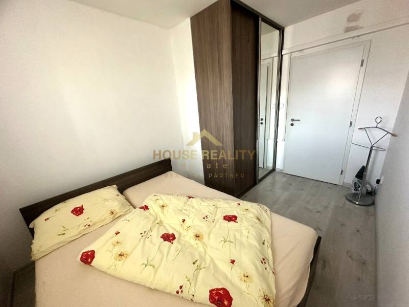 Schlafzimmer in einer 2-Zimmer-Wohnung mit Bett, Einbauschrank und Bodenbelag in Holzoptik.
