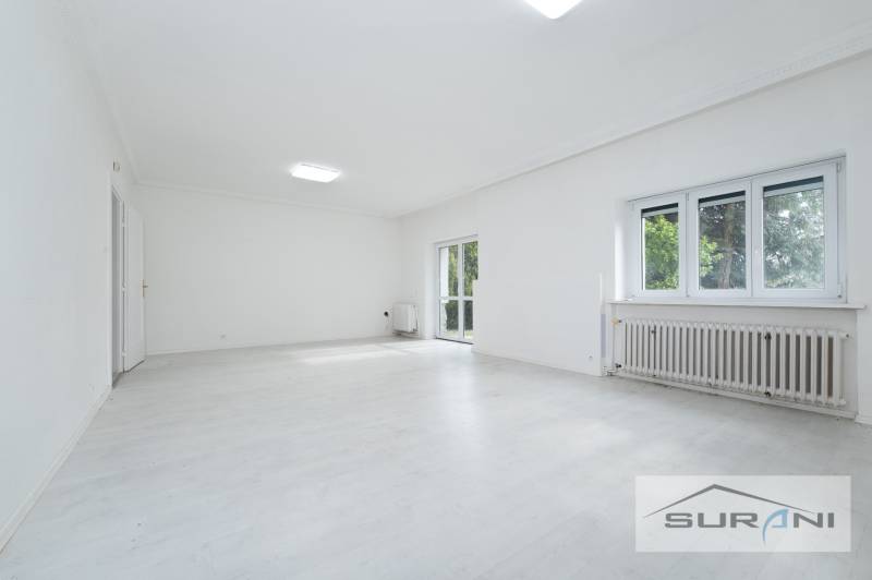 Geräumiges Wohnzimmer in einer 4-Zimmer-Wohnung mit weißem Boden und großen Fenstern.