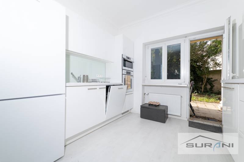 Küche mit weißen Schränken und Zugang zur Terrasse in einer 4-Zimmer-Wohnung.