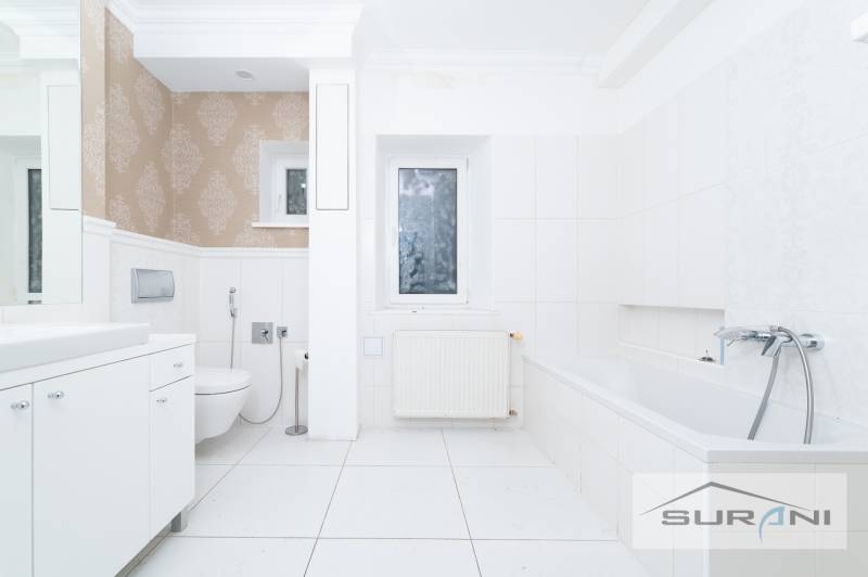 Badezimmer mit Dusche und Badewanne in einer 4-Zimmer-Wohnung, weiße Fliesen, gemusterte Tapete.