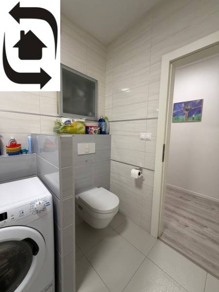 Badezimmer mit Waschmaschine, Toilette und Fliesen in einer 2-Zimmer-Wohnung.