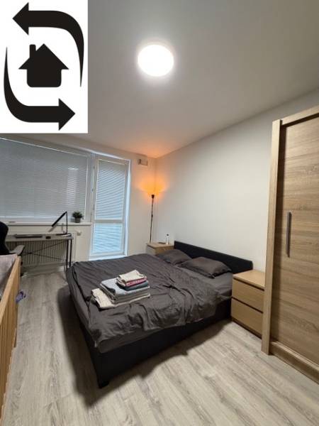Schlafzimmer in einer 2-Zimmer-Wohnung mit Holzboden und einem Bett neben dem Fenster.