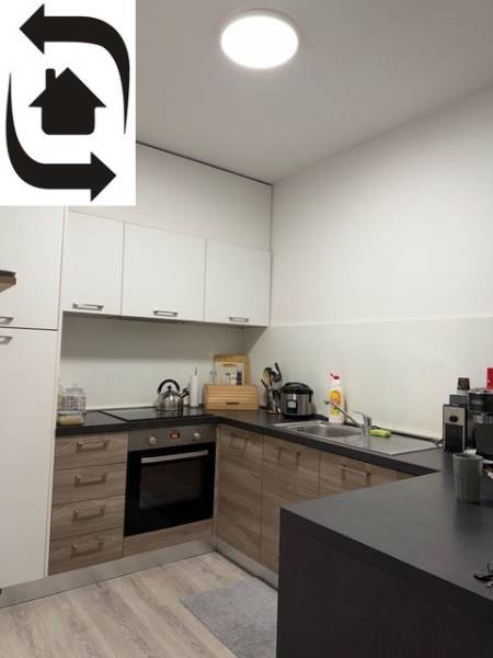Küche in einer 2-Zimmer-Wohnung mit Holzboden und weißen Schränken.