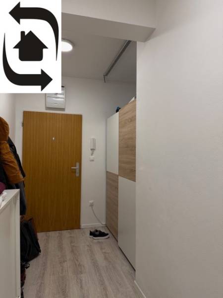 Eingangsflur in einer 2-Zimmer-Wohnung, weiße Wände und Türen, Boden mit Holzdekor.