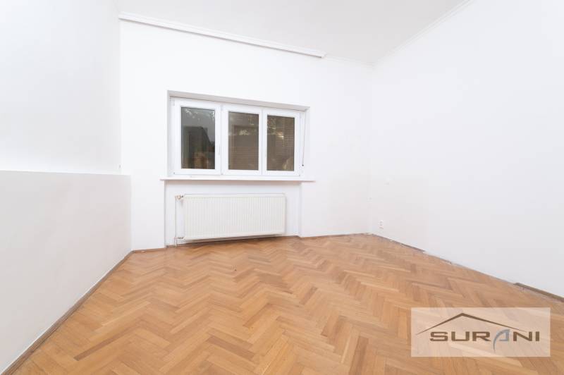 Ein Zimmer in einer 4-Zimmer-Wohnung mit weißen Wänden und einem Boden in Holzoptik.