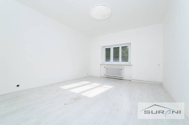 Ein leerer Raum mit weißen Wänden und einem Boden in Holzoptik in einer 4-Zimmer-Wohnung.