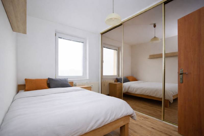 Schlafzimmer in einer 3-Zimmer-Wohnung mit Holzboden und großem Spiegelschrank.