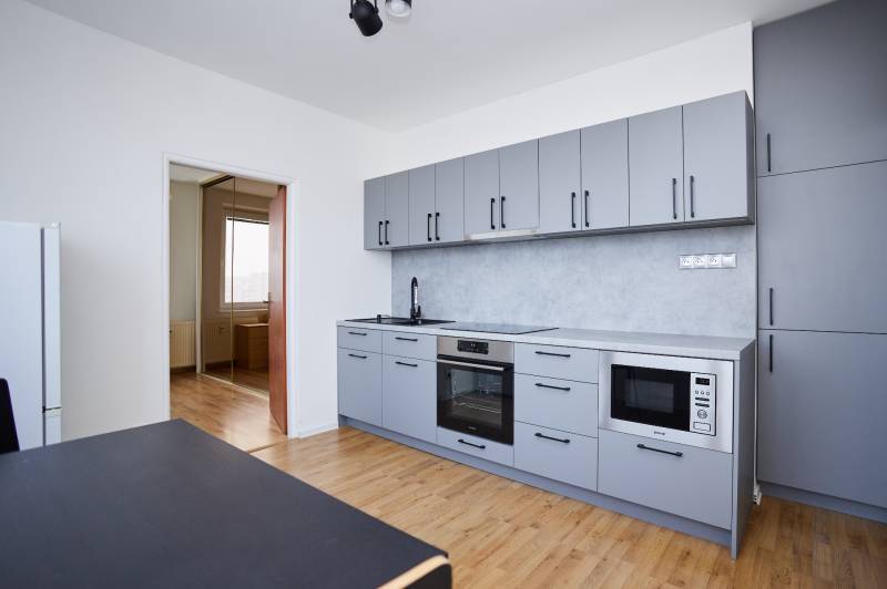 Küche in einer 3-Zimmer-Wohnung mit modernen Geräten und einem Boden in Holzoptik.