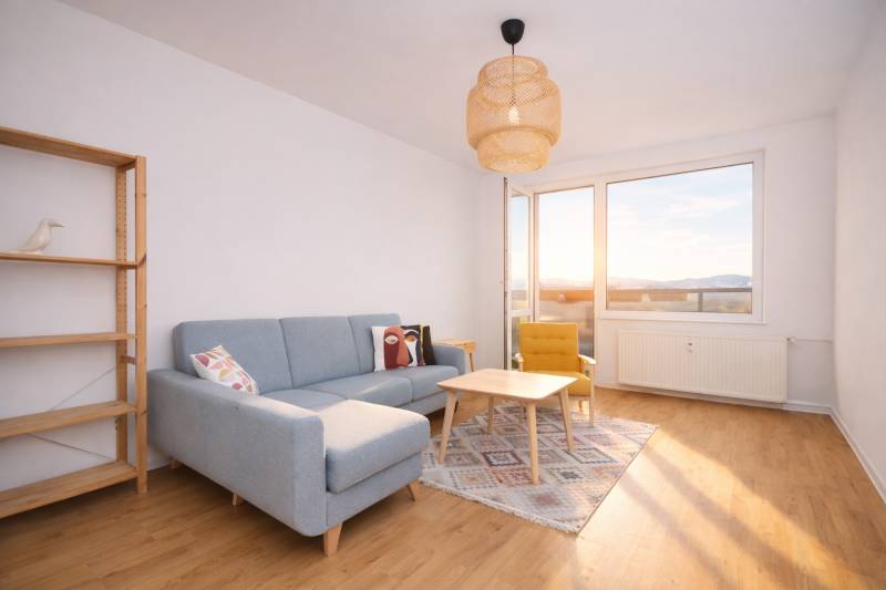 Wohnzimmer einer 3-Zimmer-Wohnung mit Sofa, Sessel und Holzboden.