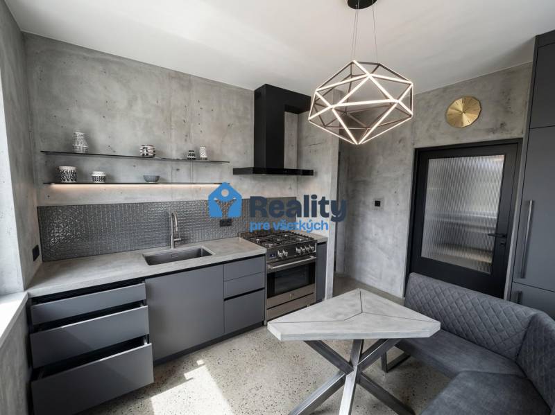 Küche in einer 2-Zimmer-Wohnung mit Betonoptik und geometrischer Leuchte.