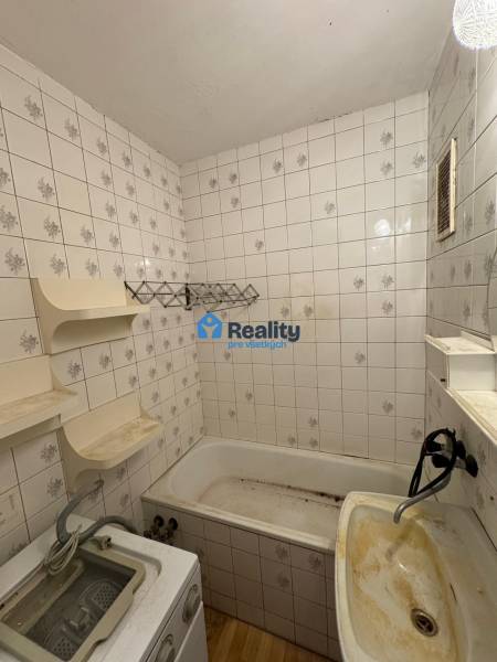 Badezimmer in einer 2-Zimmer-Wohnung mit Badewanne, Waschbecken und Fliesen.