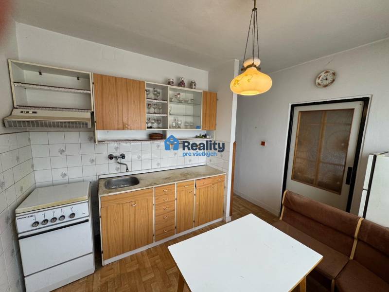 Küche in einer 2-Zimmer-Wohnung mit Küchenzeile, Tisch, Bank und Boden mit Holzdekor.