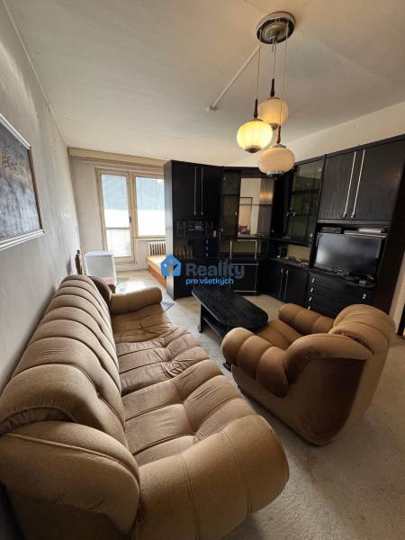 Wohnzimmer in einer 2-Zimmer-Wohnung mit einem bequemen Sofa und einer Schrankwand.
