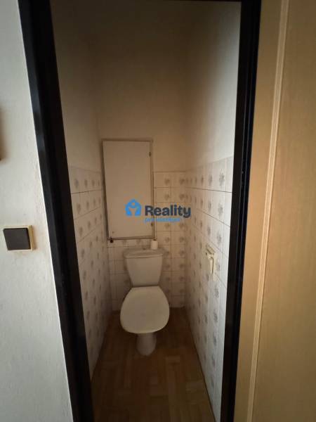 Toilette mit Fliesen und Holzboden in einer 2-Zimmer-Wohnung.