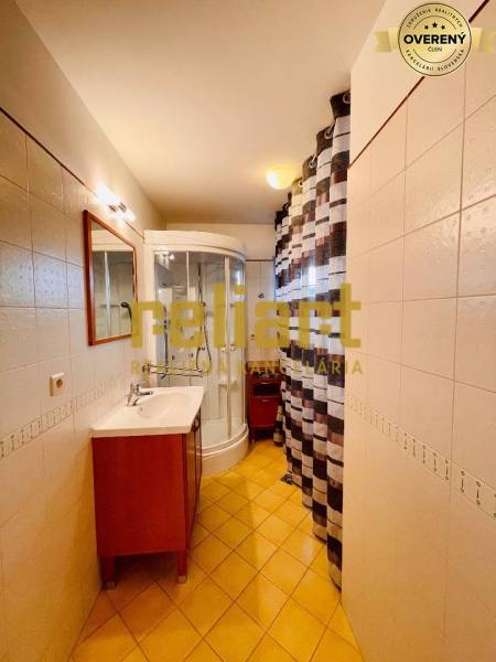 Ein Badezimmer in einem Einfamilienhaus mit Waschbecken, Duschkabine und Fliesen.