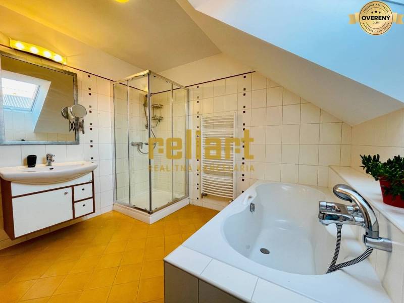 Ein Badezimmer in einem Einfamilienhaus mit Badewanne, Dusche und schräger Decke.
