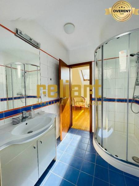 Badezimmer mit Dusche und Waschbecken, Boden mit Holzdekor in einem Einfamilienhaus.