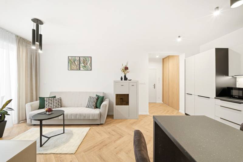 Wohnzimmer in einer 4-Zimmer-Wohnung mit einem weißen Sofa und einem Boden in Holzoptik.