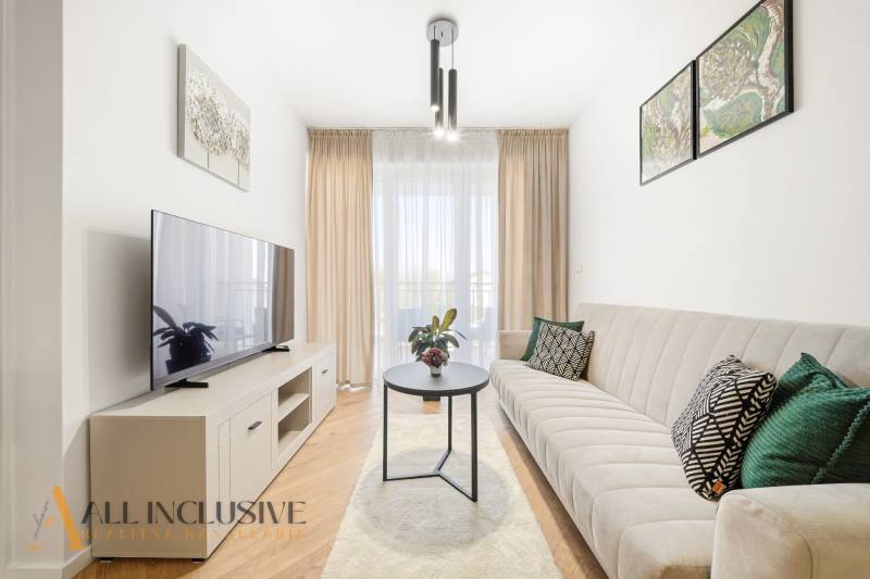 Wohnzimmer in einer 4-Zimmer-Wohnung mit Holzboden, hellen Möbeln und einem Sofa.
