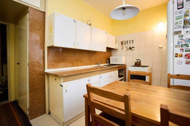 Küche mit Holztisch in einer 3-Zimmer-Wohnung. Schränke, Herd, Kühlschrank mit Magneten.