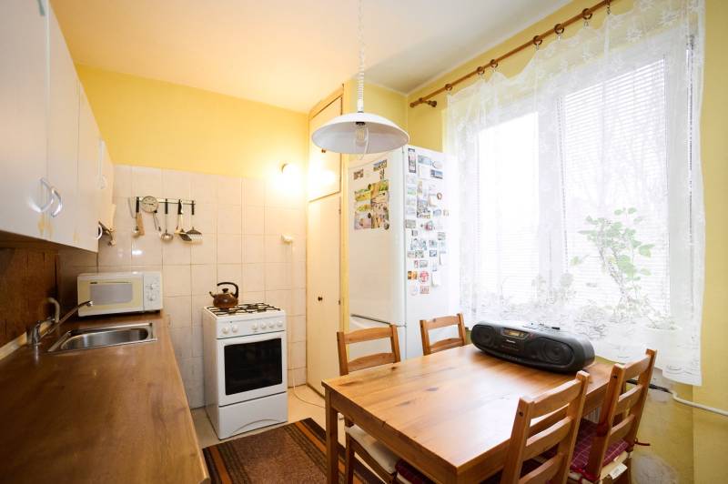 Küche in einer 3-Zimmer-Wohnung mit einem Holztisch, Herd und weißer Küchenzeile.