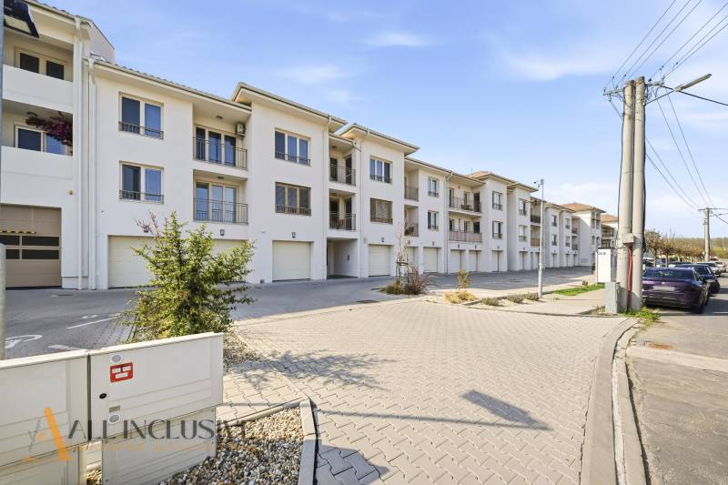Ein Komplex aus weißen Gebäuden und Parkplätzen in Dunajská Streda, ideal für eine 4-Zimmer-Wohnung.