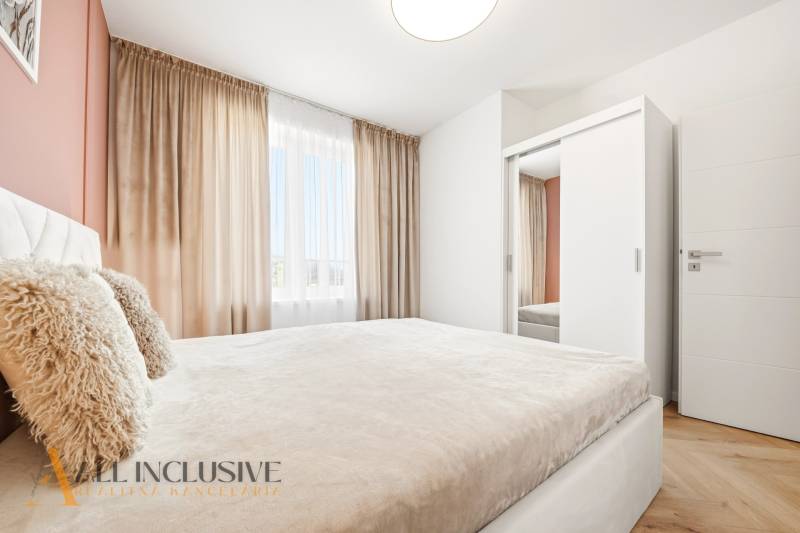 Helles Schlafzimmer in einer 4-Zimmer-Wohnung mit weißem Schrank und Vorhängen.