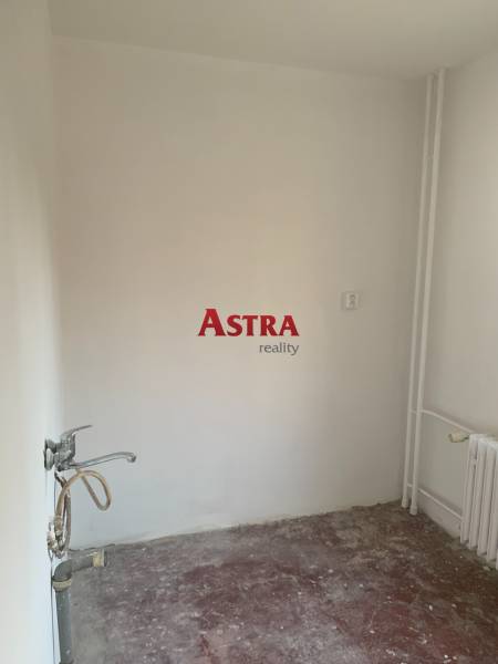 Ein leerer Raum in einer 2-Zimmer-Wohnung ohne Bodenbelag und mit Waschbecken.