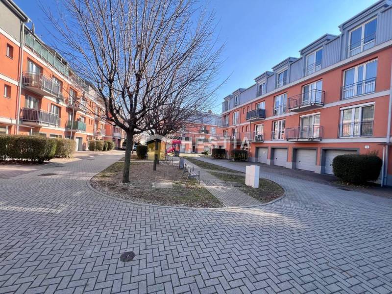 Wohnkomplex mit orangefarbenen Fassaden, Bäumen und gepflegten Gehwegen. Geeignet für eine Einzimmerwohnung.