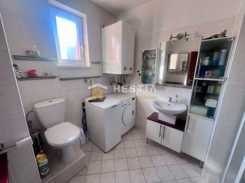 Das Badezimmer in der Einzimmerwohnung bietet eine Toilette, eine Waschmaschine und Regale am Fenster.