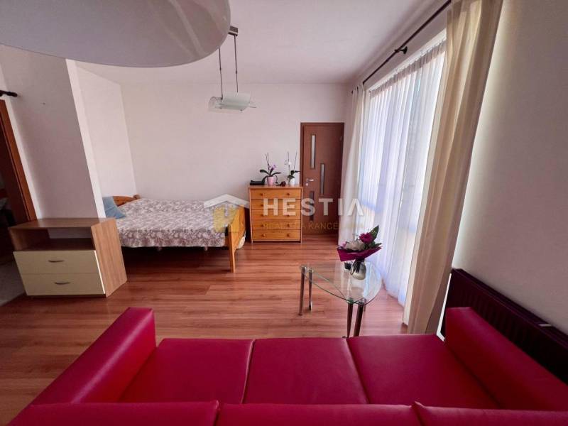 Auf dem Foto ist eine Einzimmerwohnung zu sehen, die ein Bett, ein rotes Sofa und einen Glastisch umfasst.