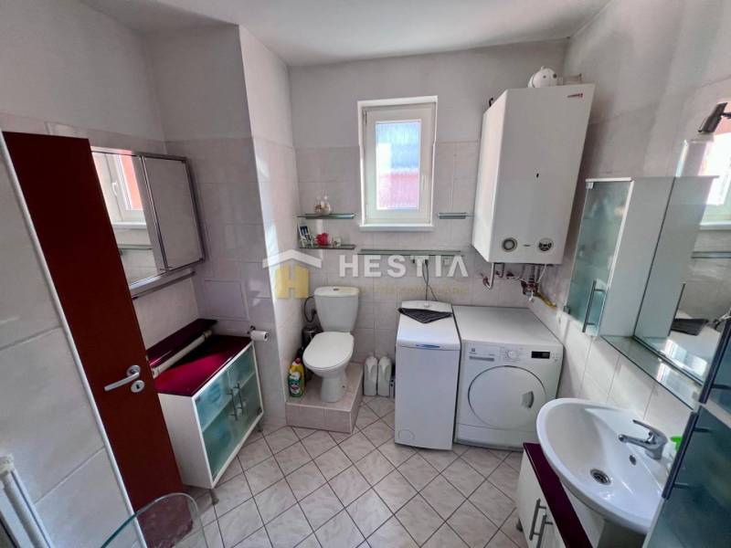 Das Badezimmer enthält eine Waschmaschine, Schränke, eine Toilette und ein Waschbecken, geeignet für eine Einzimmerwohnung.