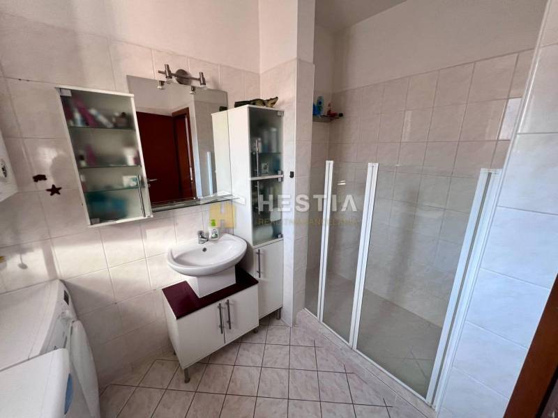 Badezimmer mit Dusche, Waschbecken und Stauraum in einer Einzimmerwohnung.