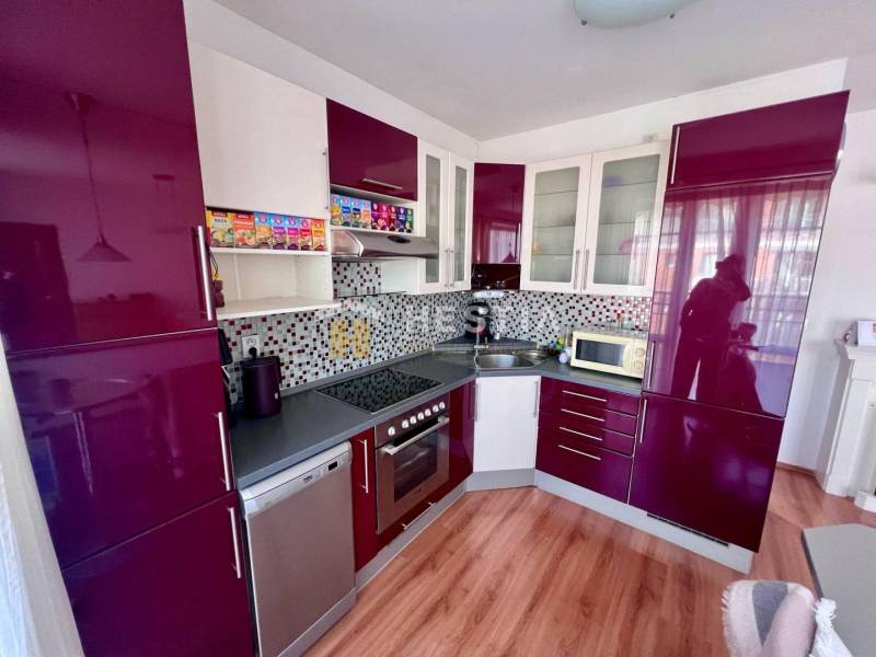 Küche in einer Einzimmerwohnung mit glänzenden Schränken und Mosaik an der Wand.