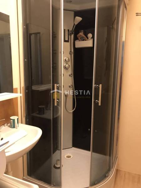 Badezimmer mit Dusche und Waschbecken in einer 2-Zimmer-Wohnung.