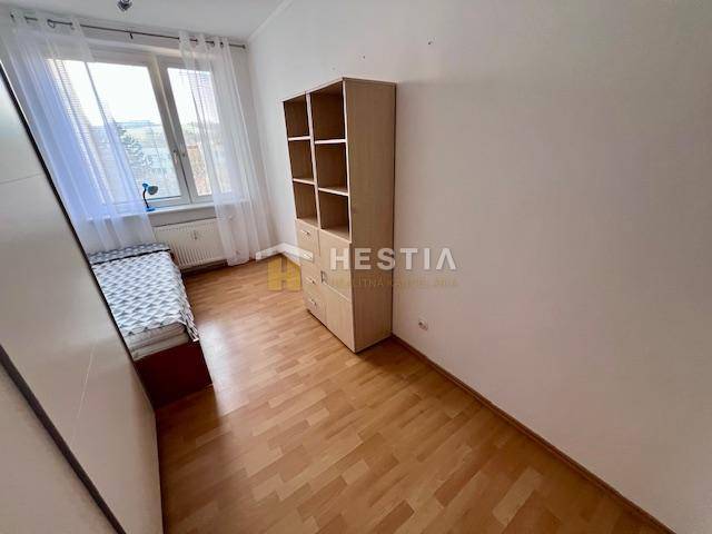 2-Zimmer-Wohnung, Bett am Fenster, Regal, Boden mit Holzdekor, weiße Wand.