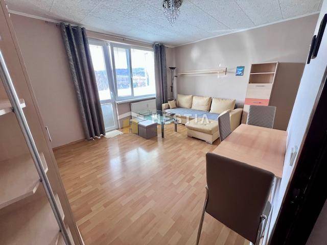 Wohnzimmer einer Zweizimmerwohnung mit Holzboden und hellen Möbeln.