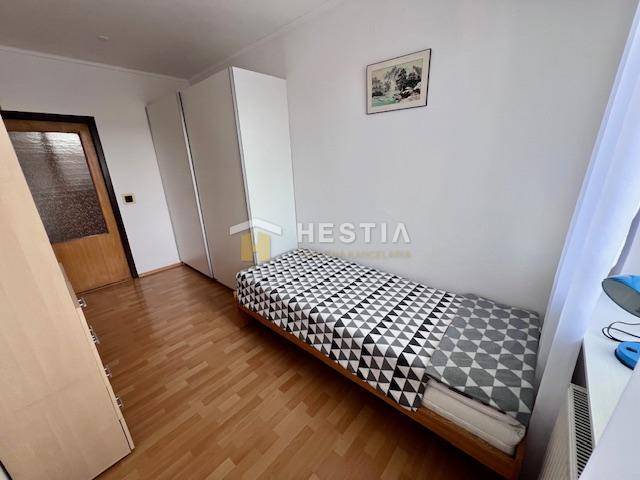 Ein Zimmer in einer 2-Zimmer-Wohnung mit einem Bett, einem Kleiderschrank und einem Boden in Holzoptik.